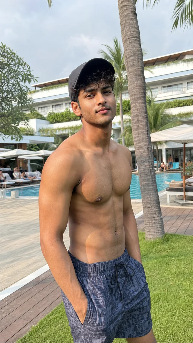 Fictional AI-generated adult man in swim shorts by a pool.